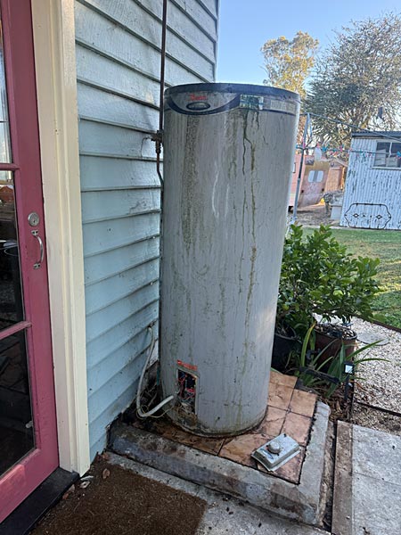 2 old hot water system leaning off the wall